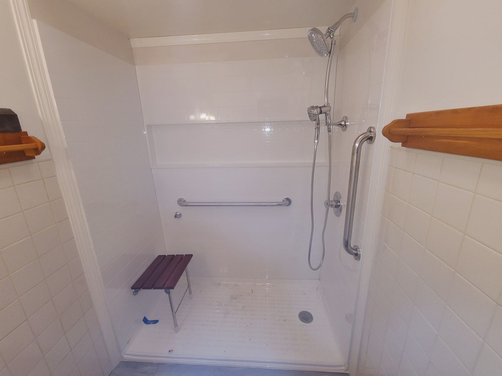 Accessible shower with a fold-down seat, grab bars, and a handheld shower