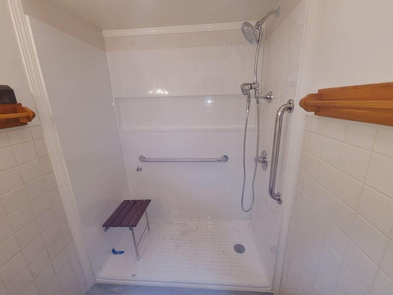 Accessible shower with a fold-down seat, grab bars, and a handheld shower