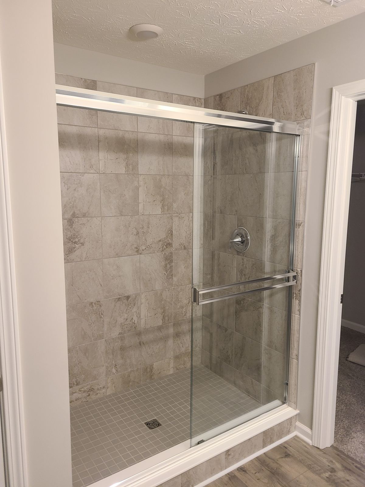 Tiled walk-in shower with a sliding glass enclosure